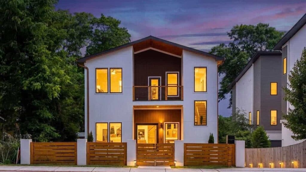 Memorial Drive Residence at dusk: full front elevation, two-story modern home with dark gable, lit interior windows