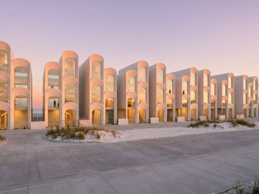 PCB Emerald in elevation, a row of arched-facade nine-key townhouses on the Panama City Beach shore at dusk.